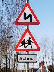 Double bend first to left sign and School children crossing sign. UK Road Traffic Triangular Warning  Signs