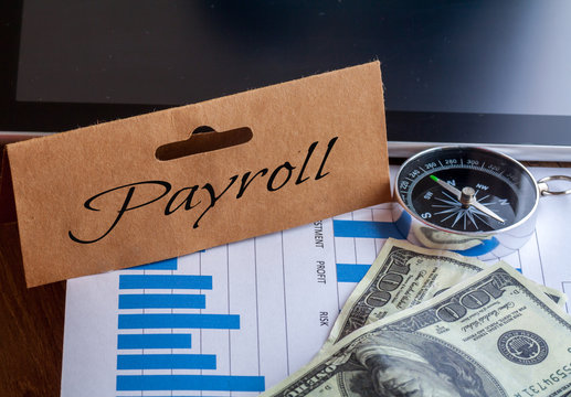 Payroll Words on tag with dollar note,smartphone,compass and graph on wood backgroud,Finance Concept