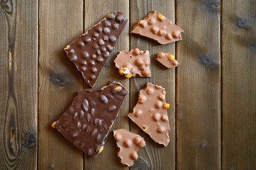 broken pieces of real Swiss lump chocolate with nuts on wooden background