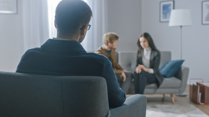 Unfocused Couple on Counseling Session with Psychotherapist. Focus on Back of Therapist Taking...
