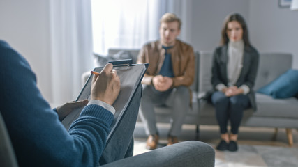 Couple on a Counseling Session with Psychotherapist. Foreground Focus on Back of the Therapist...