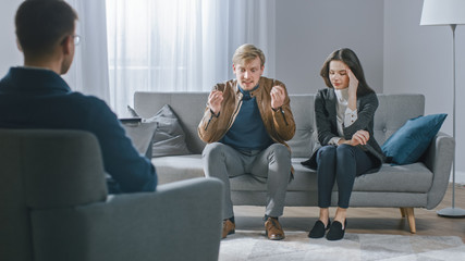 Young Couple on Counseling Session with Psychotherapist. Back View of Therapist Taking Notes: Angry Boyfriend loses Temper, Starts to Shout at His Suffering Girlfriend. Domestic Violence