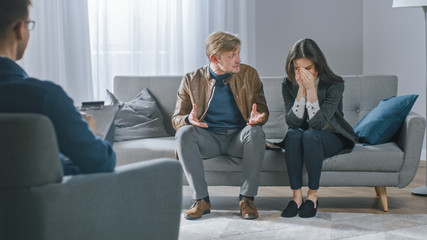Young Couple on Counseling Session with Psychotherapist. Back View of Therapist Taking Notes: Angry Boyfriend loses Temper, Starts to Shout at His Suffering Girlfriend. Domestic Violence