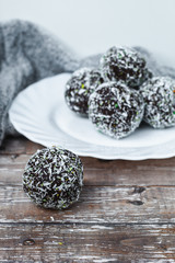 rum chocolate balls with coconut flakes on tray. Sweet raw vegan balls. Chocolate, coconut, dates and banana. Wooden background. Healthy lifestyle. 