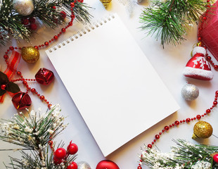 flatlay with christmas pine tree, leaves, sketchbook , bells, red christmas toys