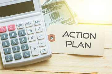 ACTION PLAN Words on tag with dollar note and calculator on wood backgroud,Finance Concept