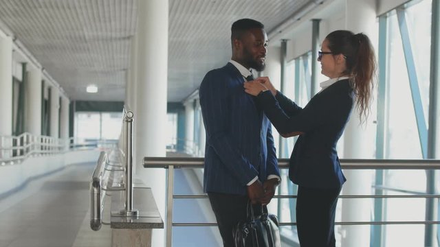 Multiracial business couple standing together and communicating in office hallway