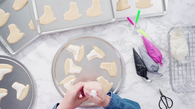 Flat lay. Decorating ice skate shaped sugar cookies with white color royal icing.