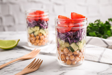 Healthy salad in glass jars on marble table