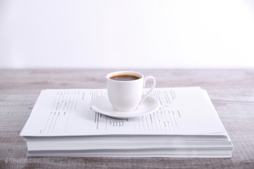 Take a break drink coffee concept. Cup of coffee on a stack of paper on the table