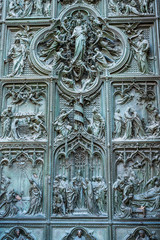 Beautiful bas-reliefs on the bronze door of  building of the Milan Cathedral (Duomo di Milano), the cathedral church of Milan, Lombardy, Italy. Dedicated to the Nativity of St Mary.