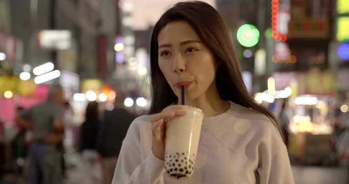 young woman enjoy bubble milk tea with street food in  Night Market