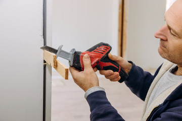 Carpenter using hackzall for cutting wooden plank Construction details of installing a wooden beam cased opening walkway between rooms