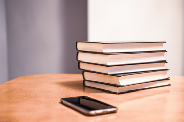 Books, print vs technology concept, stack of books and a smart phone 