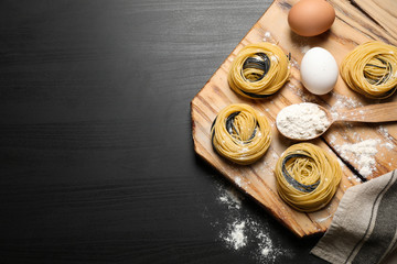 Raw linguine pasta and products on black wooden table, flat lay. Space for text
