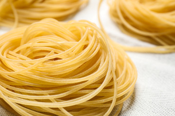 Capellini pasta on white tablecloth, closeup view