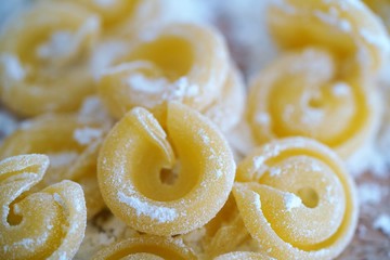 Top view on floury Italian pasta shapes on wooden background  in white flour