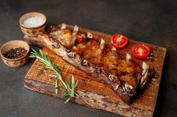 grilled pork ribs on a cutting board with spices on a stone background 