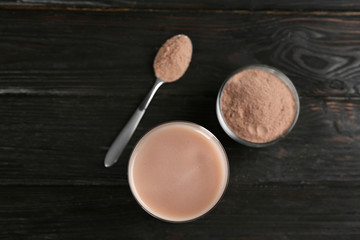 Obraz na płótnie Canvas Protein shake and powder on black wooden table, flat lay