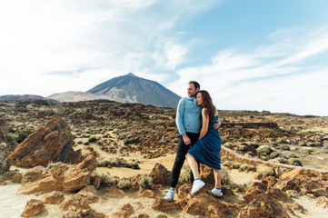 Naklejka premium Piękna młoda para kochanków pozowanie na skalistym polu na tle wulkanu