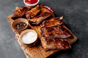grilled pork ribs on a cutting board with spices on a stone background 
