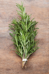 Bunch of fresh rosemary on wooden table, top view