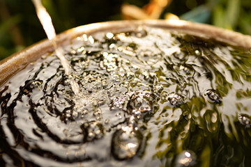 Water from tap fall droping on surface water on moring and blurred background