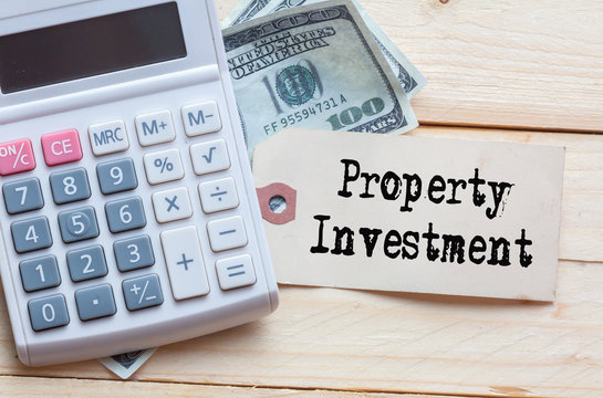 Property Investment Words on tag with dollar note and calculator on wood backgroud,Finance Concept