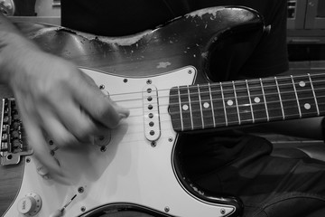 young musician playing old Electric Guitar, blured hand, black and white , play the music, with selective focus