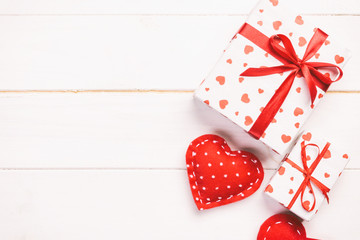 Valentine or other holiday handmade present in paper with red hearts and gifts box in holiday wrapper. Present box gift on white wooden table top view with copy space, empty space for design