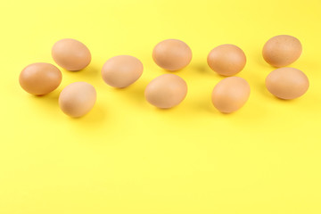 Raw chicken eggs on yellow background, above view. Space for text