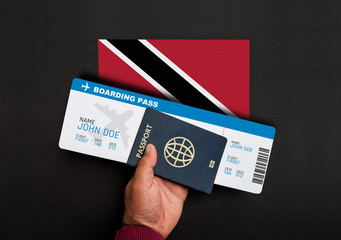 Hand holds passport and boarding pass with flag of Trinidad and Tobago