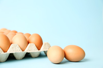 Raw chicken eggs on light blue background. Space for text
