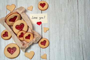 The Concept Of Valentine's Day. Homemade cakes for the holiday. A heart-shaped cookie box, a love note on a light wooden background.