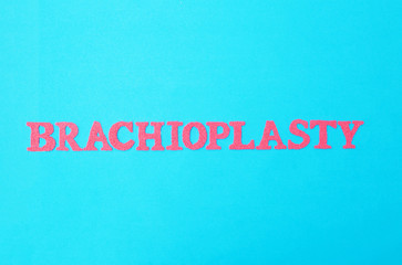 Fototapeta na wymiar The word brachioplasty in red letters on a blue background. The concept of the modern procedure in plastic surgery for lifting the skin on the hands of a person, medical