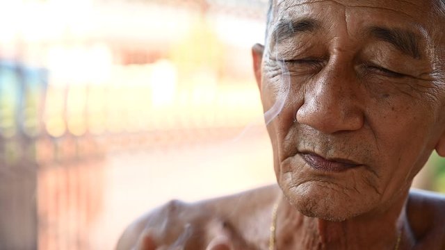 4K Close up old asian handsom man smoking cigarette outdoors. Old man smoking concept background. Man addiction tobacco, smoker poison, man's lips, smoke fire light.