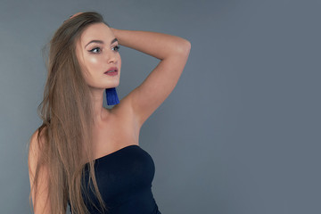 Woman with beauty long brown hair, posing at studio. long earrings classic blue