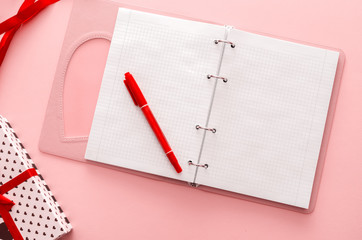 Open notebook, pen, gift. Layout on a pink background.