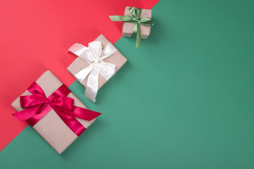 Beautiful packaging of presents with satin ribbons, craft paper on red and green background.