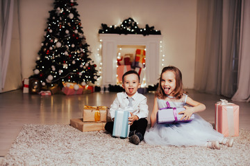Fototapeta na wymiar a boy with a girl open Christmas presents new year holiday Garland lights