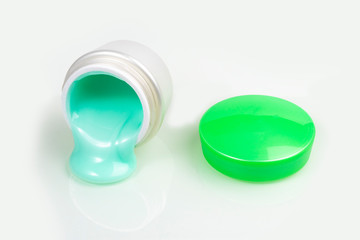 jar with cream and a green lid. the bank is open and there is a cruise nearby. close-up. on white background.