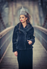 Beautiful fairy-tale winter queen in the forest with sparkling tiara and Elegant black fur coat....