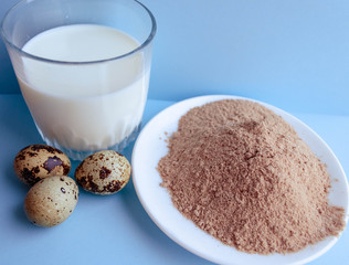 Natural organic Ingredients for making a cake, biscuit, pie, cookies, cacao flour, eggs and milk on a blue background.  homemade  with copy space. Flat lay.