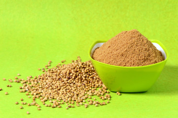 Coriander seeds and Powdered coriander in green container on green background