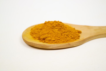 Turmeric powder in a wooden spoon on a white background