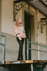 Street fashion portrait of young beautiful woman wearing beige roll neck pullover
