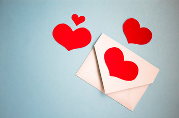 red heart made of paper, many hearts in the form of paper, red heart on a classic blue background.white holiday envelope around red hearts.the concept of Valentine's day