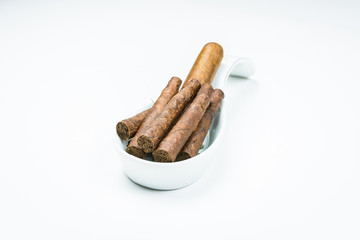 Gorgeous cigars from twisted sheets in the stand for the cook with white background.