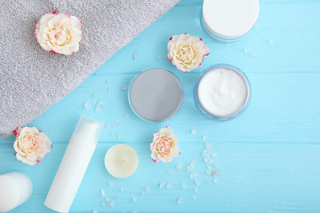 Care cream and flowers on a colored background top view. Skin care cosmetics.