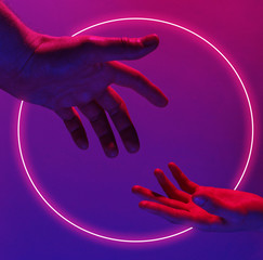 Two hands reach out to each other with pink violet neon circle. Minimalism fashion. Surrealism....